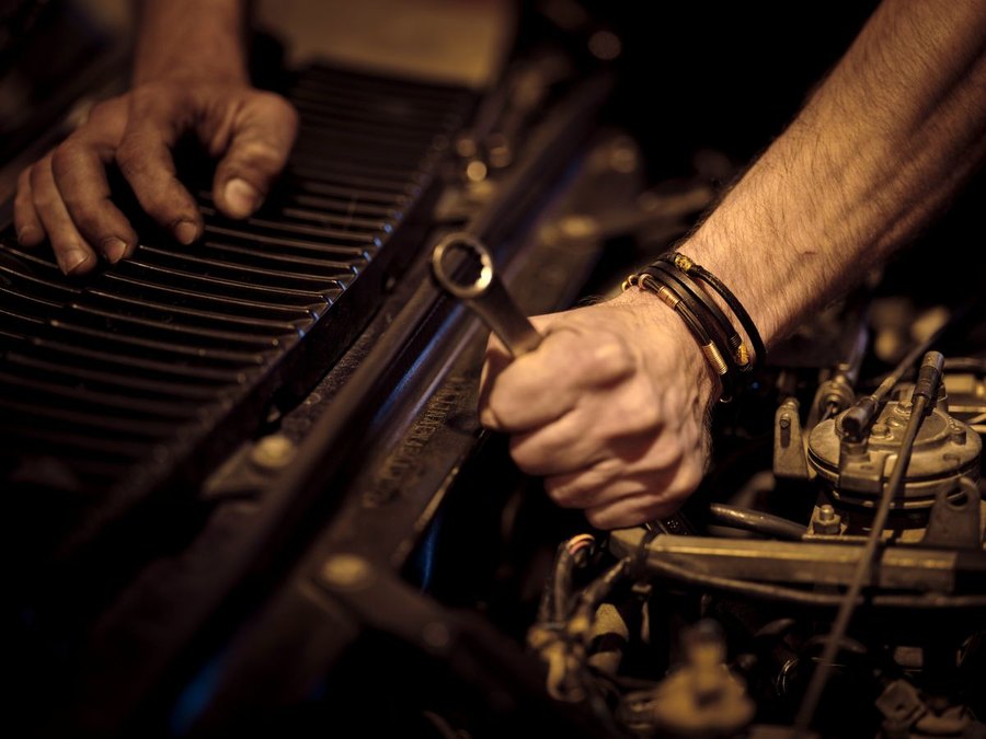 Deux mains au serrage d'une clé sur un moteur, tons chauds d'atelier